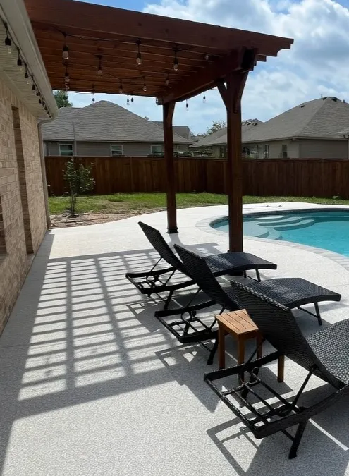 Covered patio lounge area beside a pool finished with light speckled TPV rubber surfacing